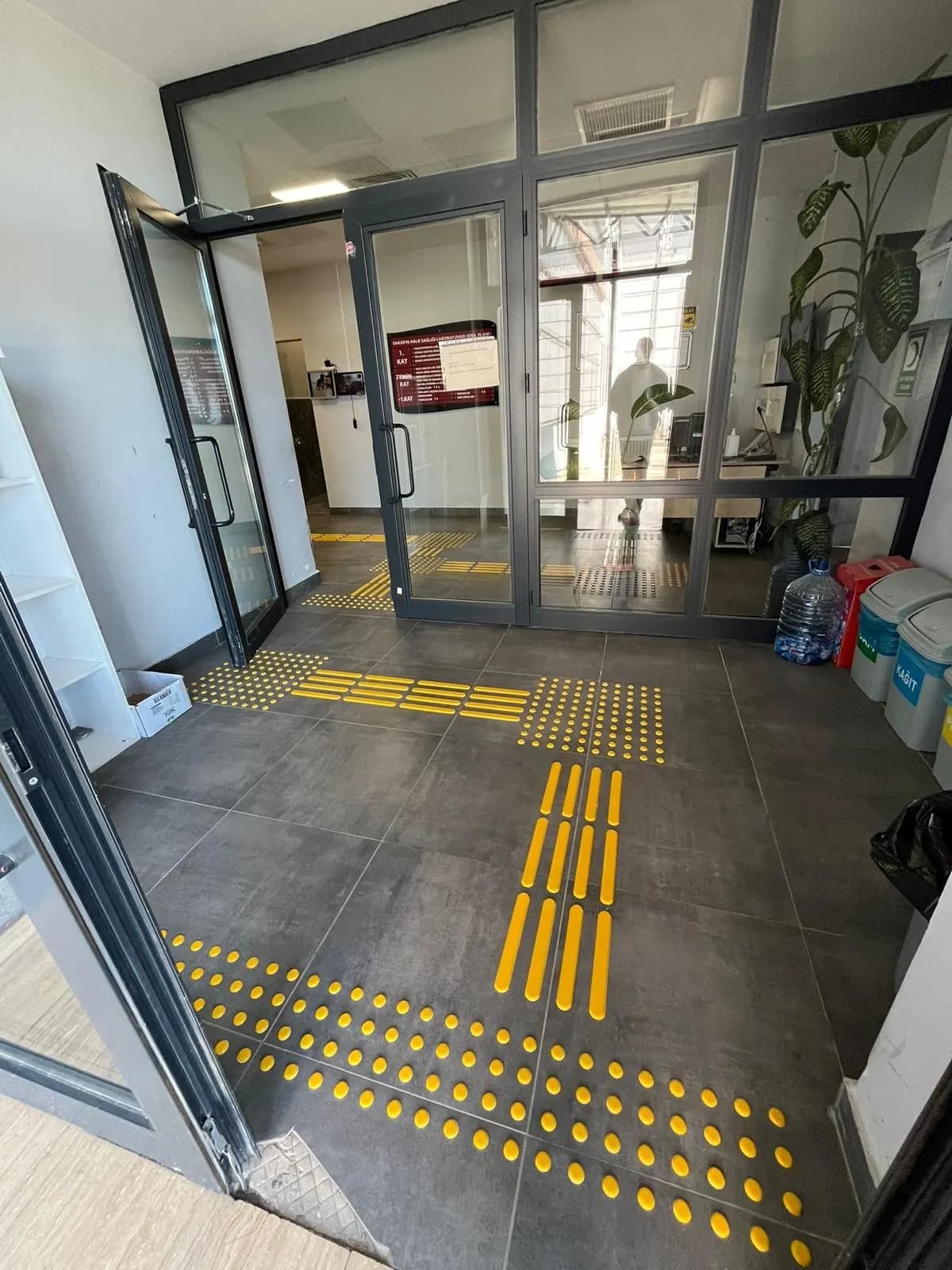 Koyu zeminde sarı PVC kılavuz ve uyarı rotası, giriş holü
