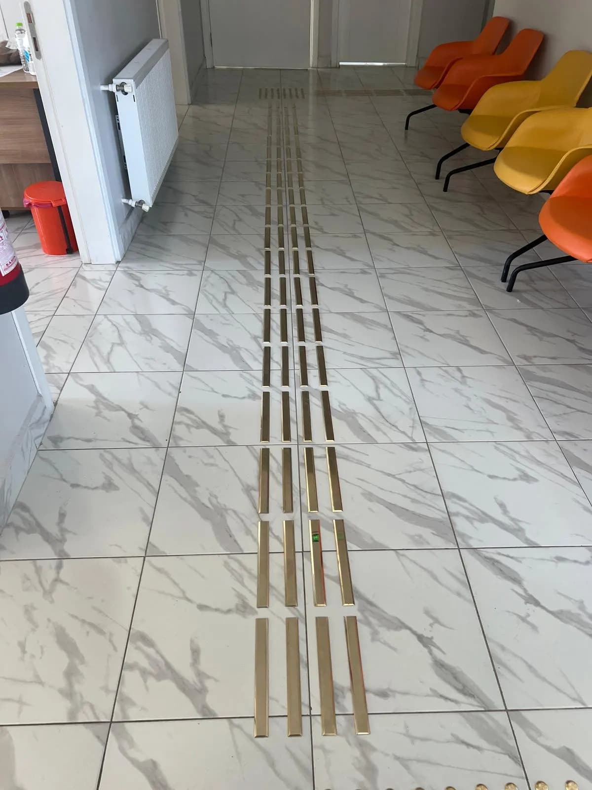 Mermer zeminde uzun pirinç kılavuz hat, bekleme koltukları boyunca